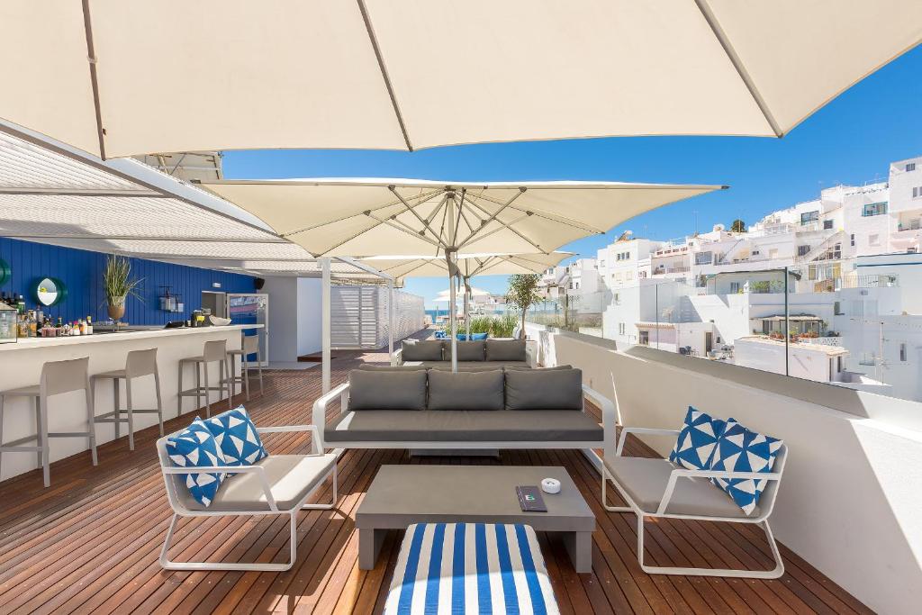 einen Balkon mit einem Tisch, Stühlen und einem Sonnenschirm in der Unterkunft Hotel Baltum in Albufeira