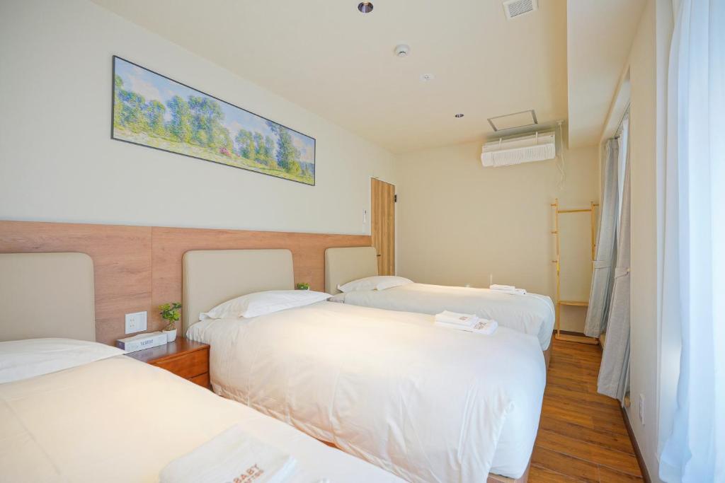 a room with three beds and a painting on the wall at Nakano World Hotel in Tokyo