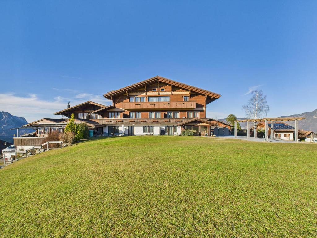 ein großes Haus auf einem Hügel mit einem großen Grasfeld in der Unterkunft Bergblick Lodge - 3 Sterne Garni - Neueröffnung in Aeschi