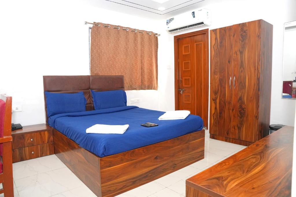 a bedroom with a bed with blue sheets and wooden furniture at Hotel Kakatiya Pride in Warangal