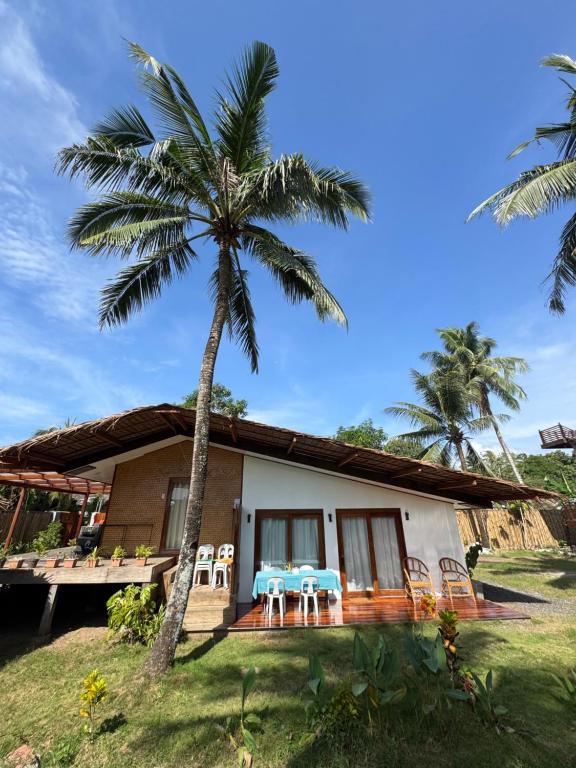 una casa con due tavoli e una palma di Surf House Palawan a San Vicente