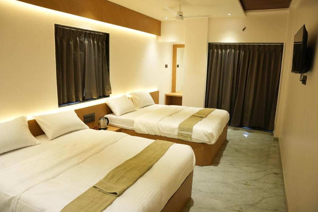 a hotel room with two beds and two windows at Hotel Nature's Nest in Shirdi