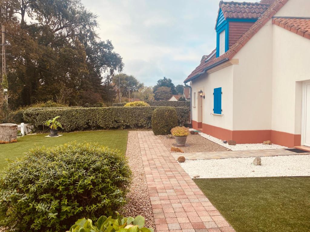 a garden with a brick walkway next to a house at Au Petit Bonheur in Cucq