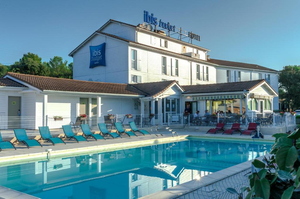 een hotel met een zwembad voor een gebouw bij ibis budget Nimes Marguerittes - A9 in Marguerittes