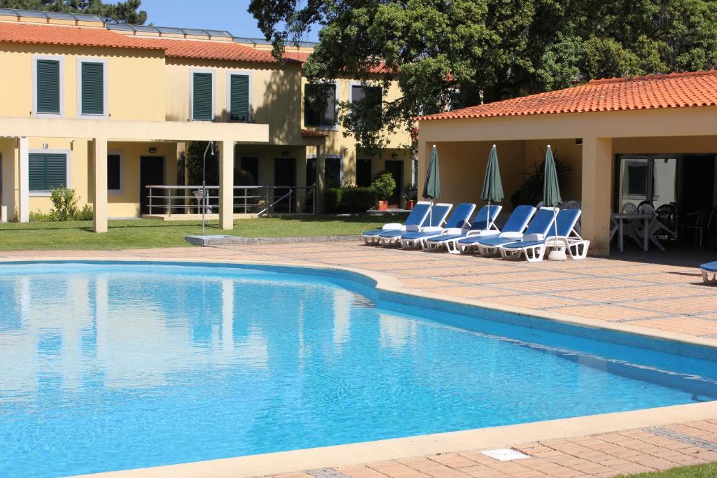 einen Pool mit Stühlen und Sonnenschirmen neben einem Haus in der Unterkunft Quinta da Boavista - Moradia E in Caminha