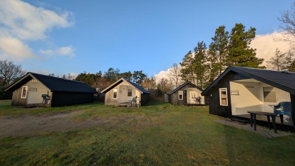 a group of houses in a field with a grass field at Henneby Camping - hytter in Henne Strand