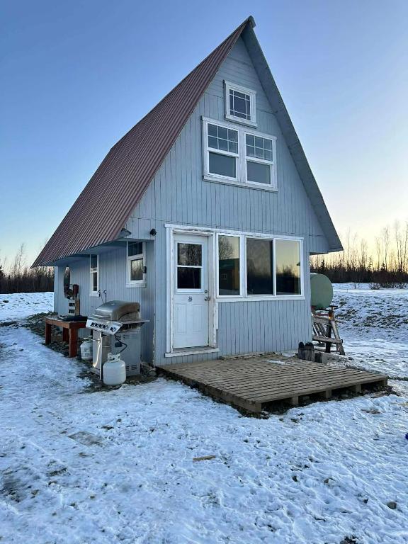 a small house with a deck in the snow at Bass Farm Lake View Loft Cabin in Wasilla
