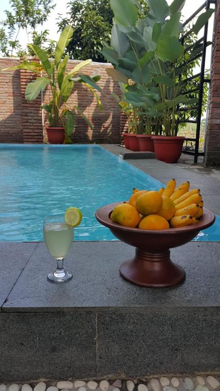 a bowl of fruit and a glass of drink next to a pool at Villa Azzyra in Pakem