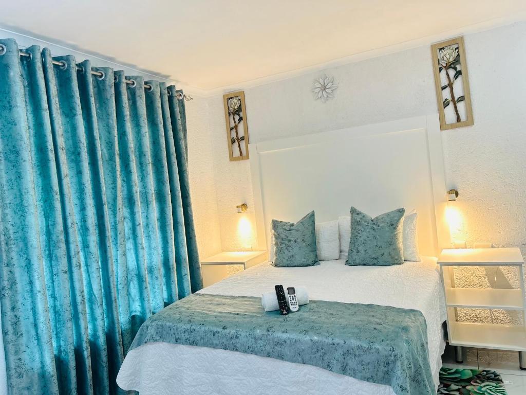 Schlafzimmer mit einem Bett mit blauen Vorhängen in der Unterkunft Duvha Guesthouse in Graskop