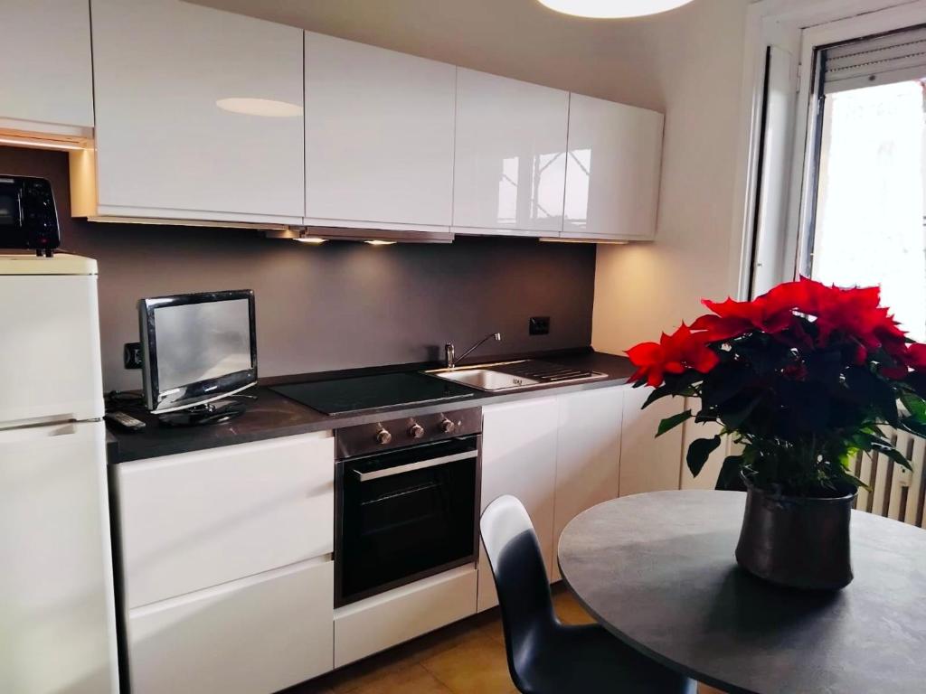 a kitchen with white cabinets and a table with red flowers at Charming Central Relais in Bergamo