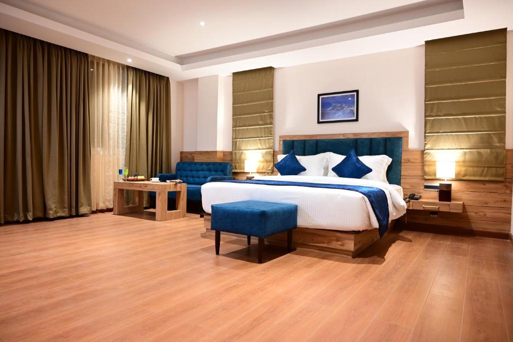 ein Schlafzimmer mit einem großen Bett und einem blauen Stuhl in der Unterkunft Click collection Gangtok in Gangtok