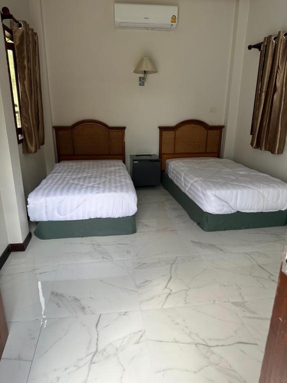 2 bedden in een kamer met een marmeren vloer bij บ้านพิมพ์วนาเขาใหญ่ ห้องมินิ in Ban Tha Maprang
