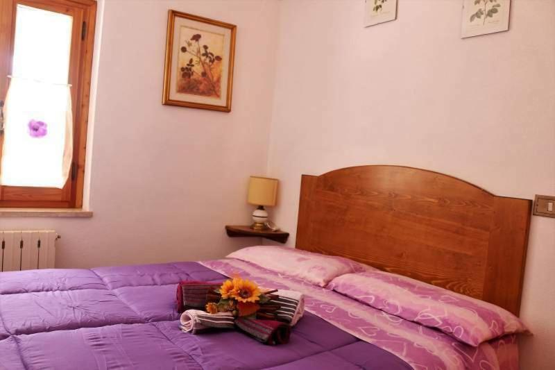 een paars bed met een boeket bloemen erop bij Appartamento Il Bosco Incantato in Abetone