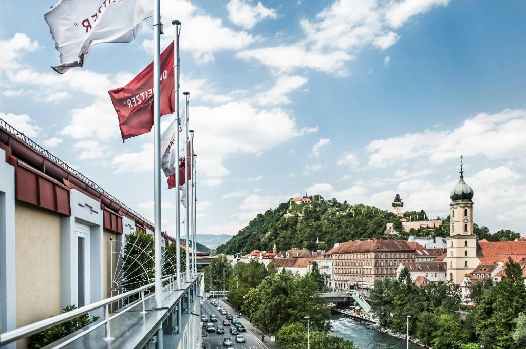 einen Balkon mit Stadtblick und Flaggen in der Unterkunft Hotel Weitzer Graz - Centre of Graz in Graz