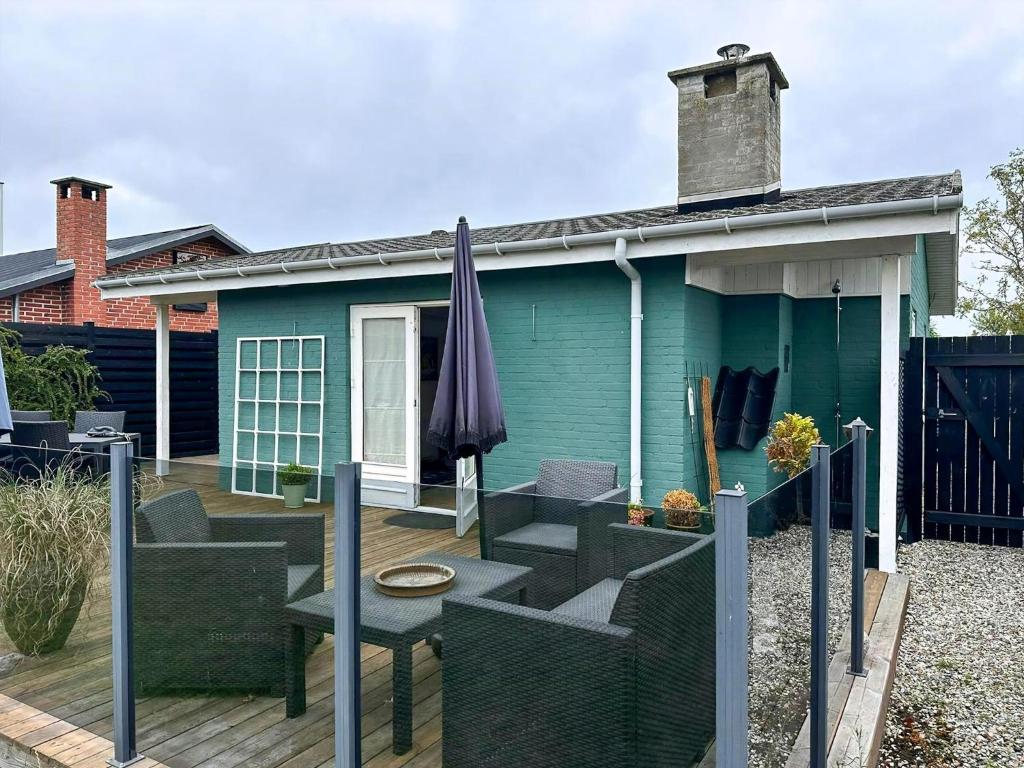 a blue house with a deck and an umbrella at Ferienhaus In Strandnähe In Otterup in Kristiansminde
