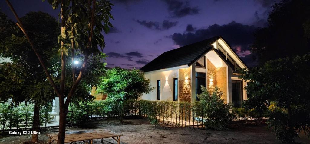 une maison la nuit avec un banc devant elle dans l'établissement กัสเกรซ โฮมสเตย์, à Pak Chong