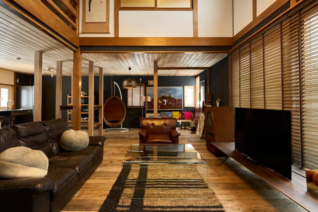 a living room with a leather couch and a television at HETA Niseko in Niseko