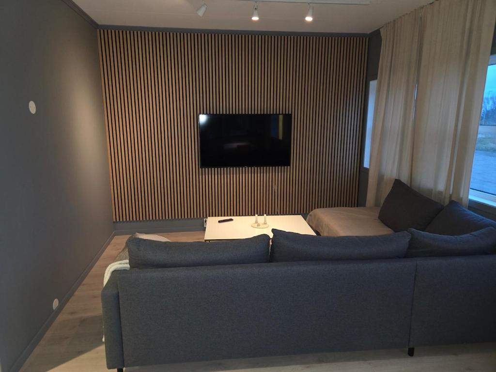 a living room with a blue couch and a flat screen tv at Aurora Andøya Suites in Andøya