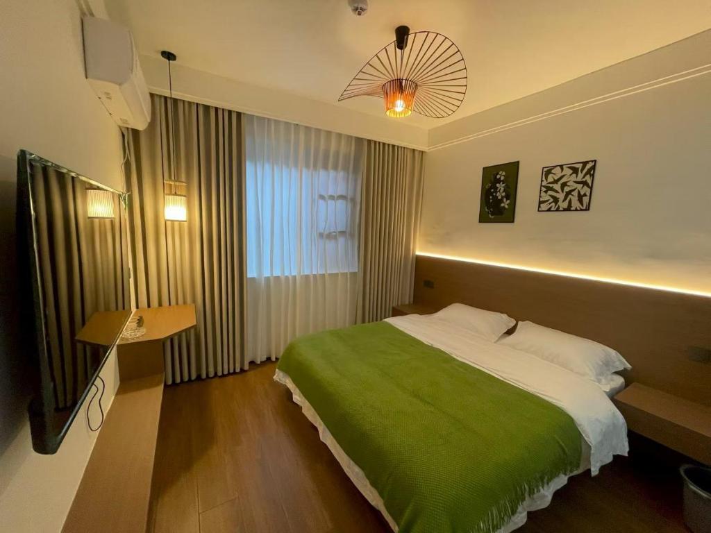 a bedroom with a large bed with a green blanket at Qingwu Lane in Luoyang
