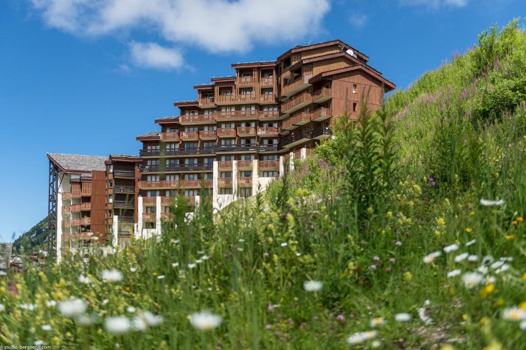 a building on a hill with a field of flowers at Résidence Pierre &amp; Vacances Les Néréides in Belle Plagne