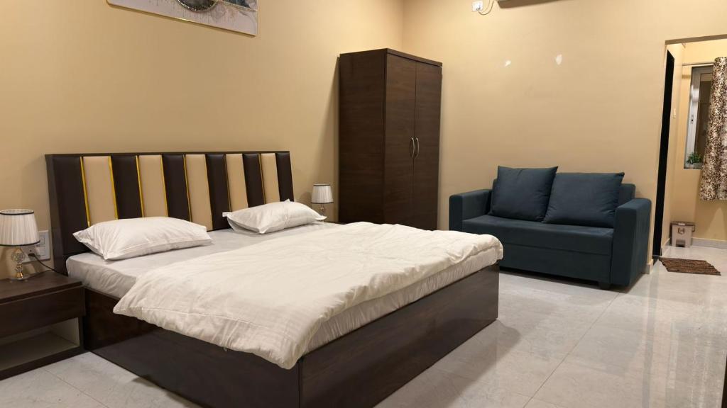 een slaapkamer met een bed en een blauwe stoel bij Mavika Stay in Navi Mumbai