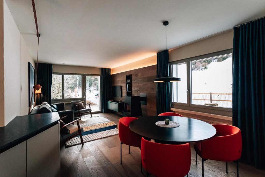 un soggiorno con tavolo e sedie rosse di Casa Partnun 4-3 a Laax-Murschetg