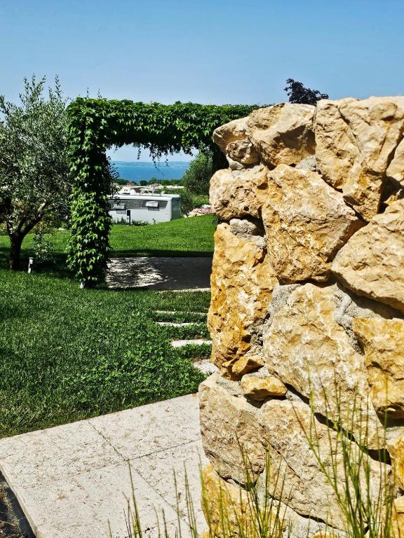 a stone wall with an arch in a yard at Agricamping Est Garda Home Rubino in Lazise