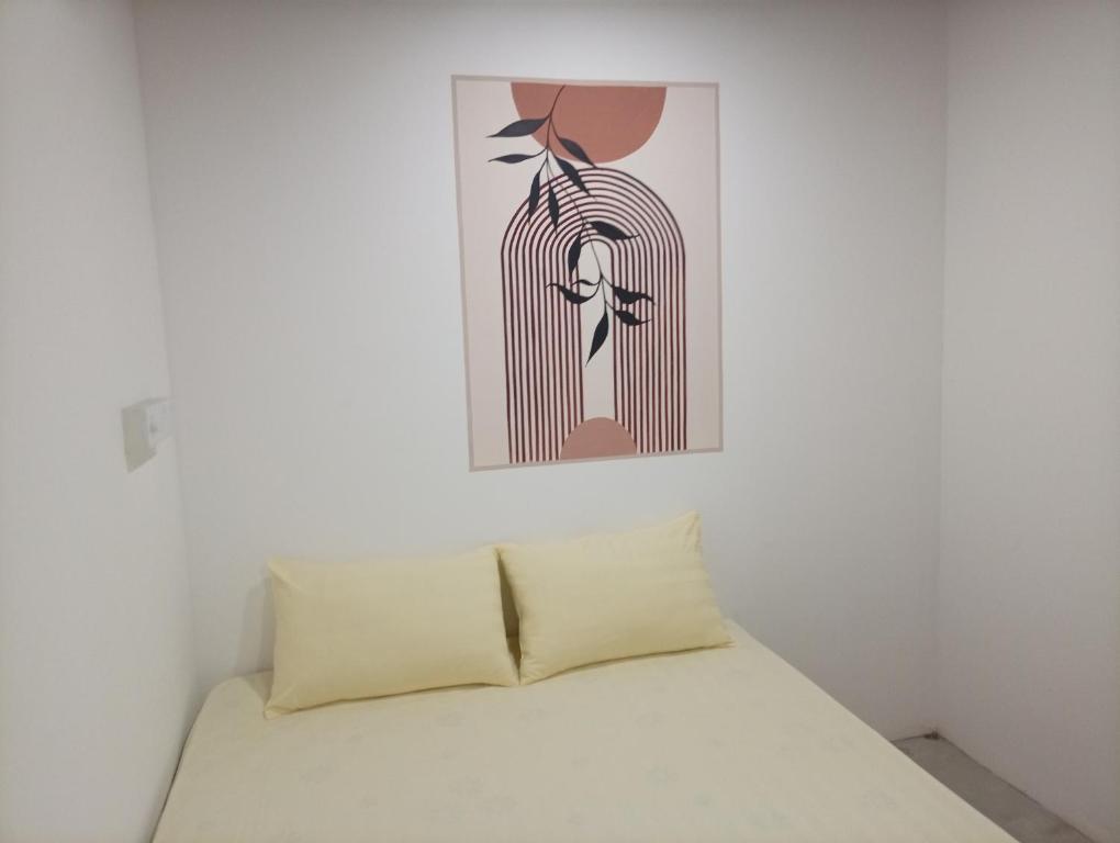 een bed in een witte kamer met een schilderij aan de muur bij Airport Transit Motel in Katunayaka