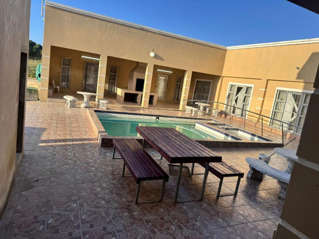 a swimming pool with benches and a picnic table and a building at Morogoro Park Lodge 