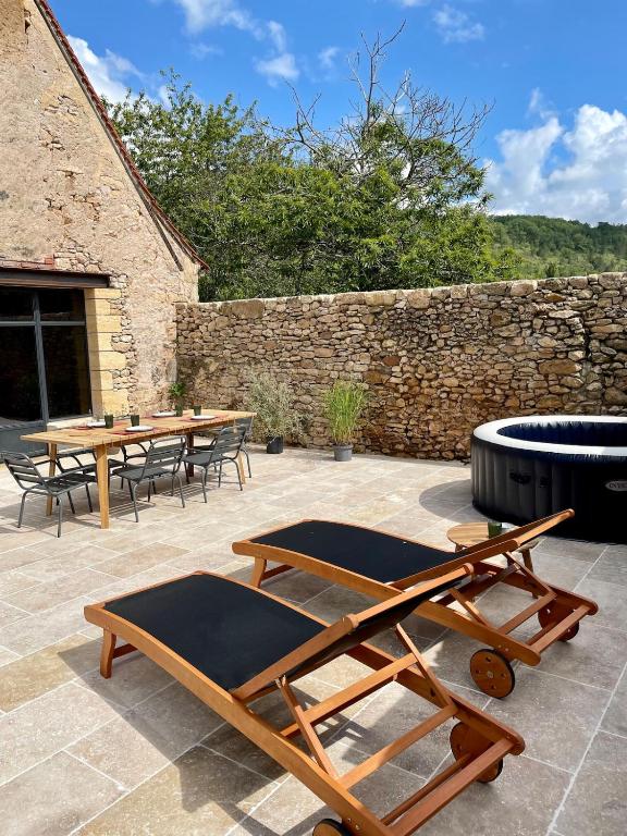 een patio met tafels en stoelen en een stenen muur bij Maison in Le Bugue