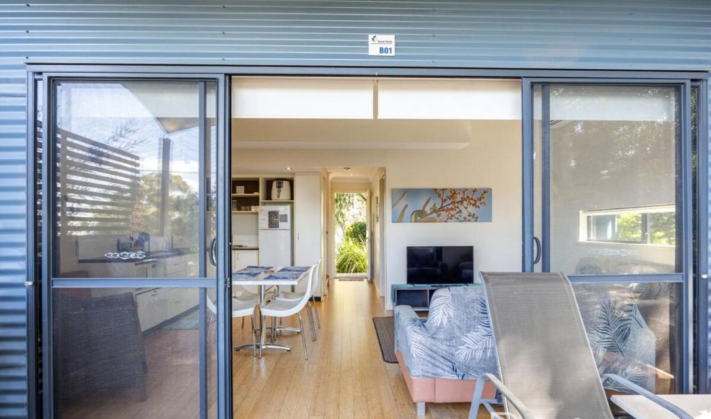 a dining room and kitchen with a sliding glass door at Relaxing Beach shack at the Footprints complex in Preston Beach