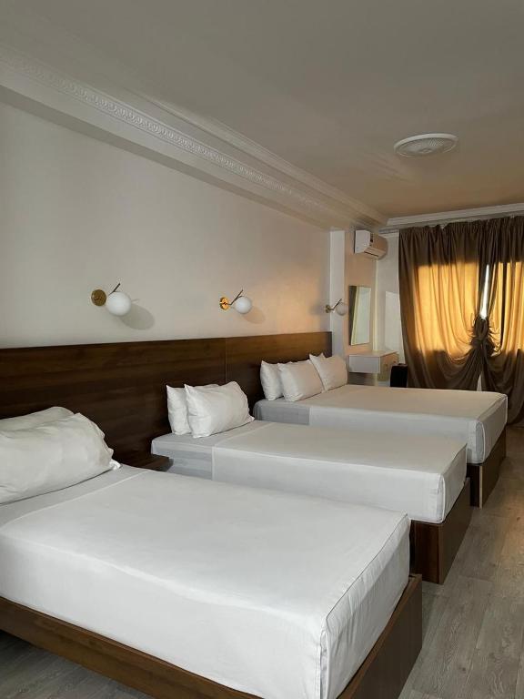 zwei Betten in einem Hotelzimmer mit weißen Laken in der Unterkunft Crystal in Tangier