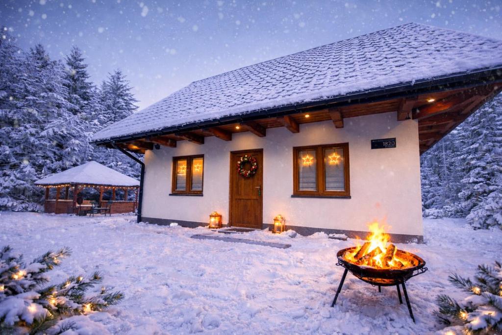 een huis met een vuur in de sneeuw bij Biały Domek Świerczek in Słopnice