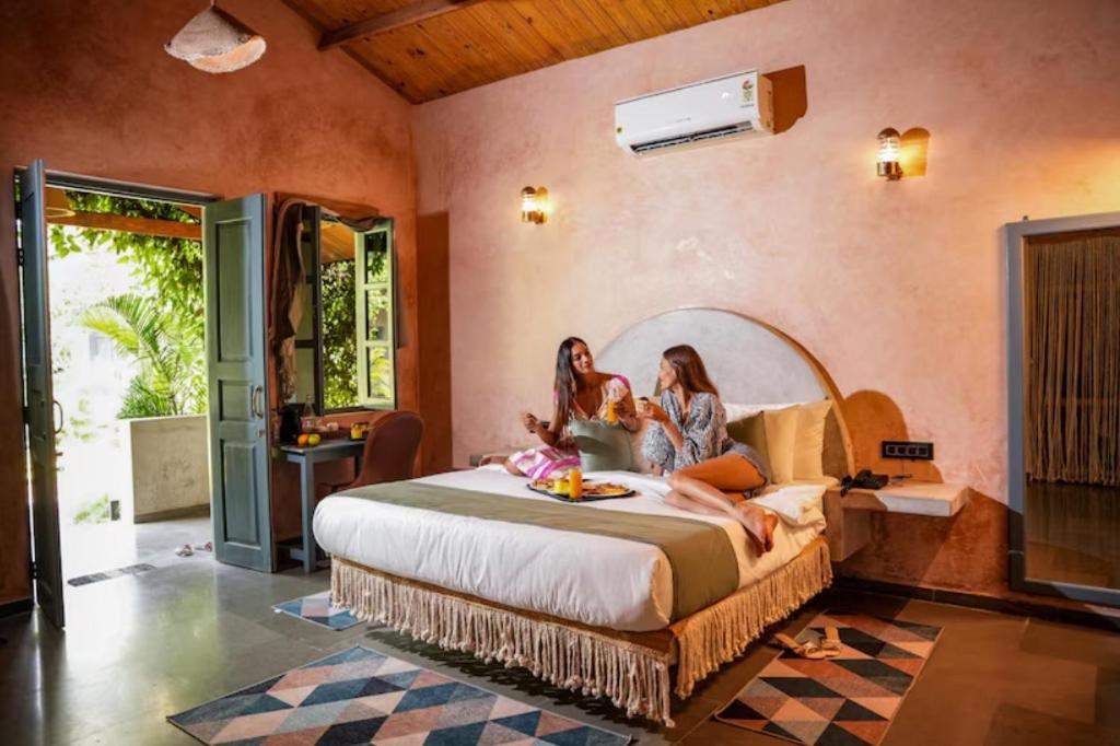 twee meisjes op een bed in een kamer bij Aqua Bella Resort in Mandrem