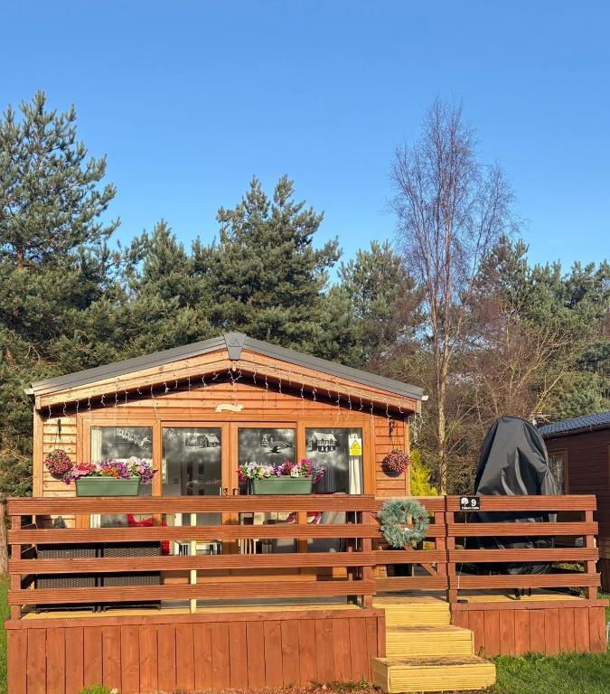 a wooden cabin with a porch and a fence at Chloe Cabin in West Thirston