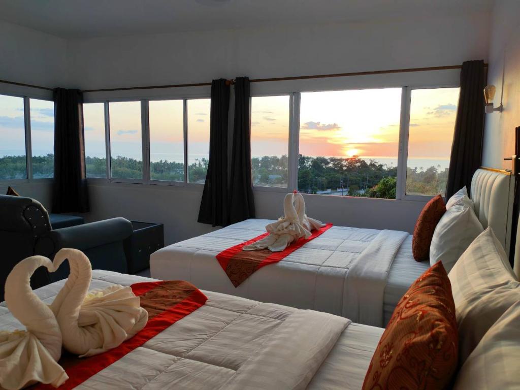 two beds in a hotel room with swans on them at Phulanta Resort in Ko Lanta