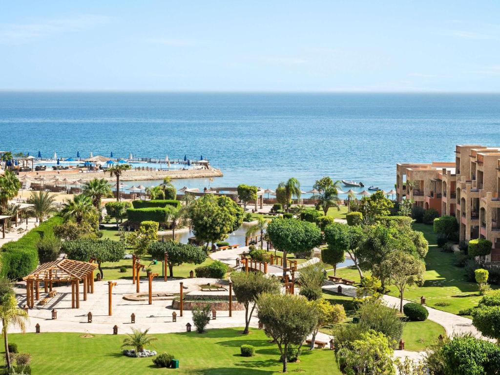ein Park am Strand mit dem Meer im Hintergrund in der Unterkunft Mövenpick Resort El Sokhna in Ain Suchna
