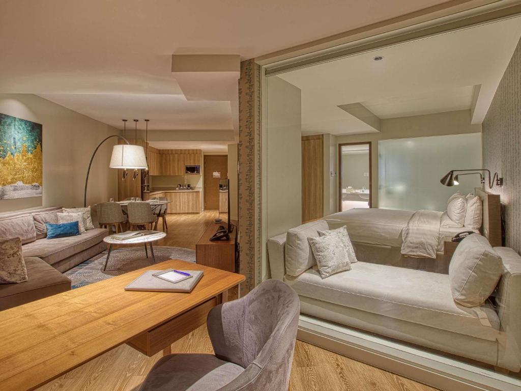 ein Schlafzimmer mit Bett und ein Wohnzimmer in der Unterkunft Novotel Suites Manila at Acqua in Manila