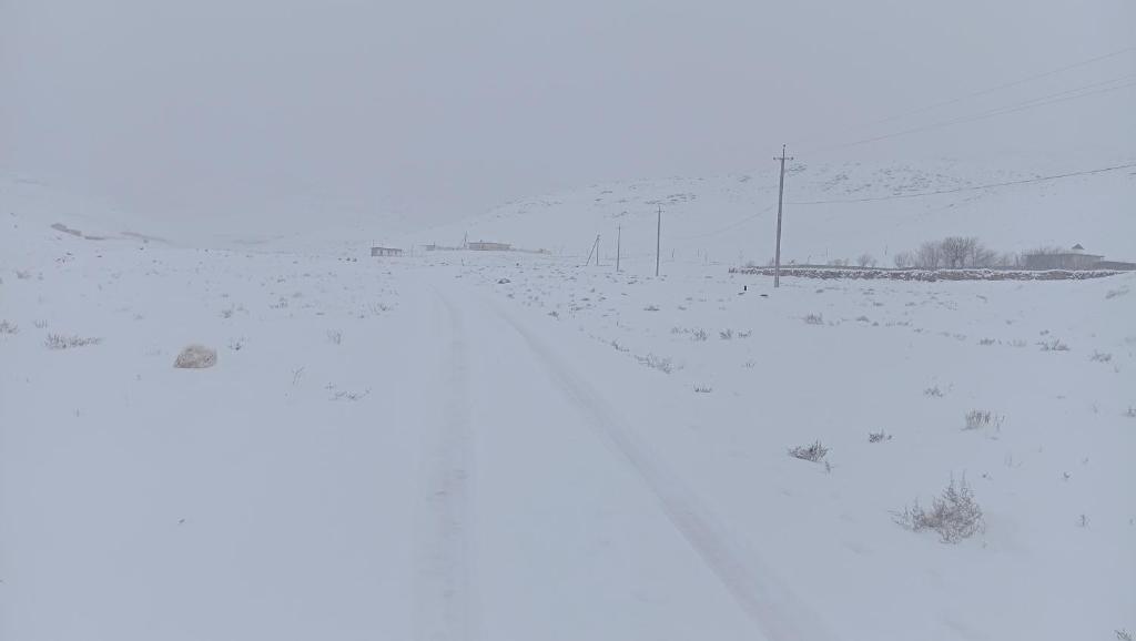 een met sneeuw bedekte heuvel met een weg en een paal bij Beautiful resort in Aydar Kul’