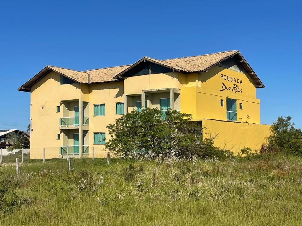 een geel gebouw bovenop een grasveld bij Pousada Reis in Imbituba