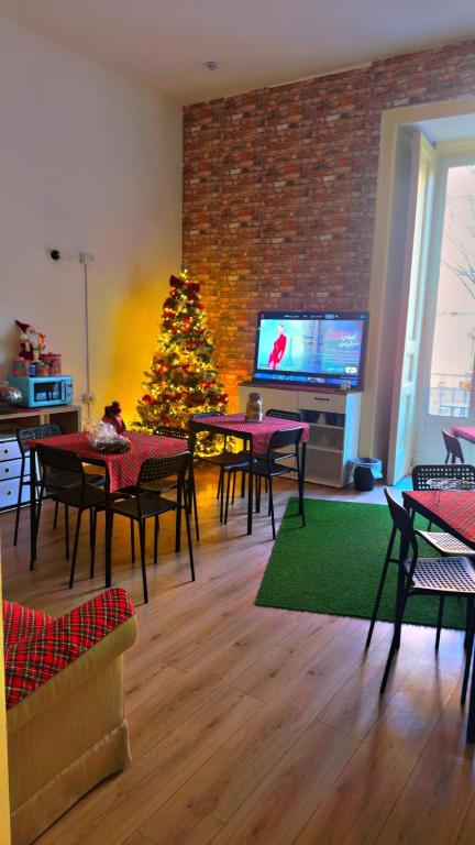een woonkamer met een kerstboom en tafels en stoelen bij Hostel Dolce di Monica in Napels