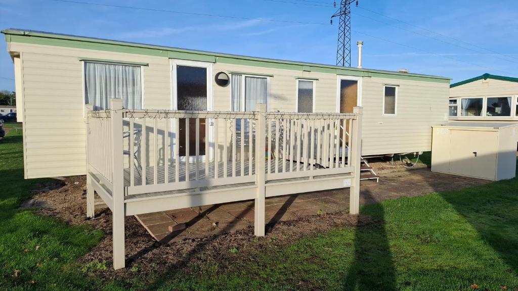 een stacaravan met een veranda en een hek bij Suntrail House in Great Clacton