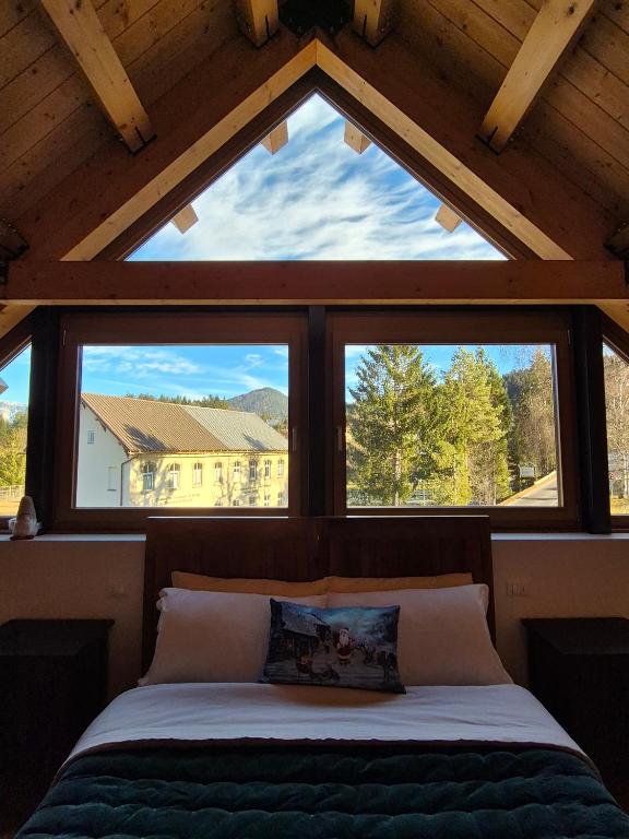 a bed in a room with three windows at NEW Locanda da Raimondo - das Knarren der Zeit in Tarvisio