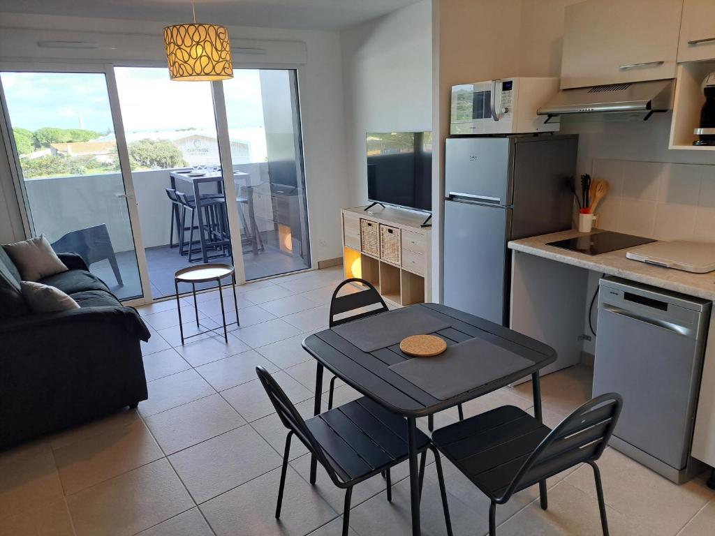 eine Küche und ein Wohnzimmer mit Tisch und Stühlen in der Unterkunft Iconic 343 , Superbe T2 climatisé, wifi, parking, terrasse 18m2 in Cap d'Agde