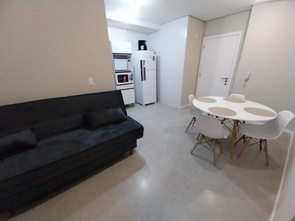ein Wohnzimmer mit einer Couch und einem Tisch und einem Kühlschrank in der Unterkunft Modern apartment steps from the beach with amenities in Arroio do Silva