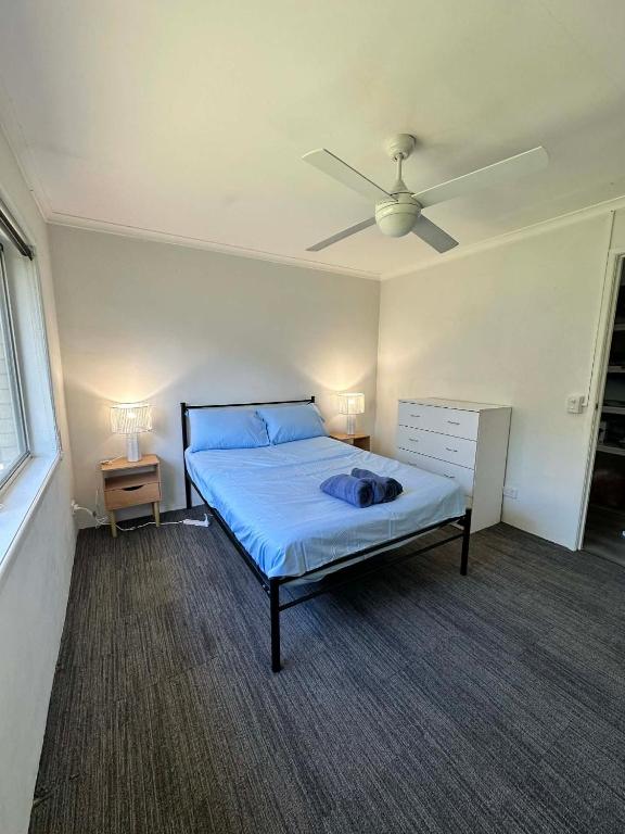 une chambre avec un lit et un ventilateur de plafond dans l'établissement Gold Coast Rooms, à Gold Coast
