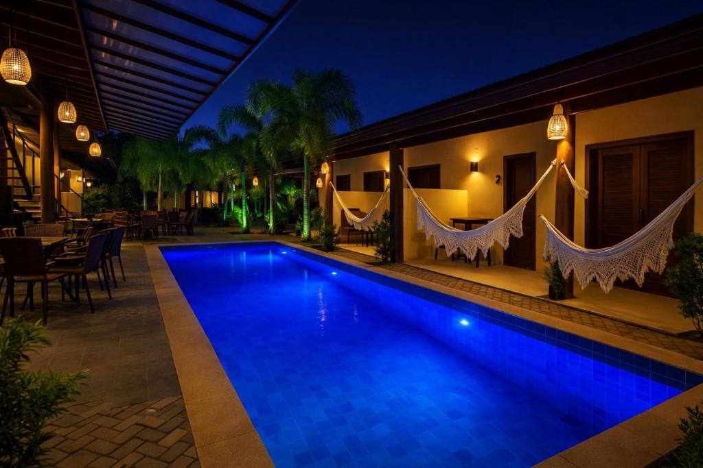 a swimming pool in front of a house at night at Pousada Charmosa Lua Nova Pipa - Chales com Jacuzzi e Hidro in Pipa