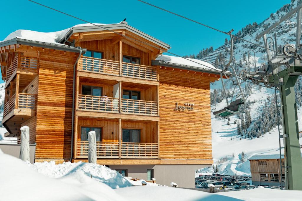 a log cabin in the mountains with snow on the ground at Apart-Hotel Laurus Lech in Lech am Arlberg