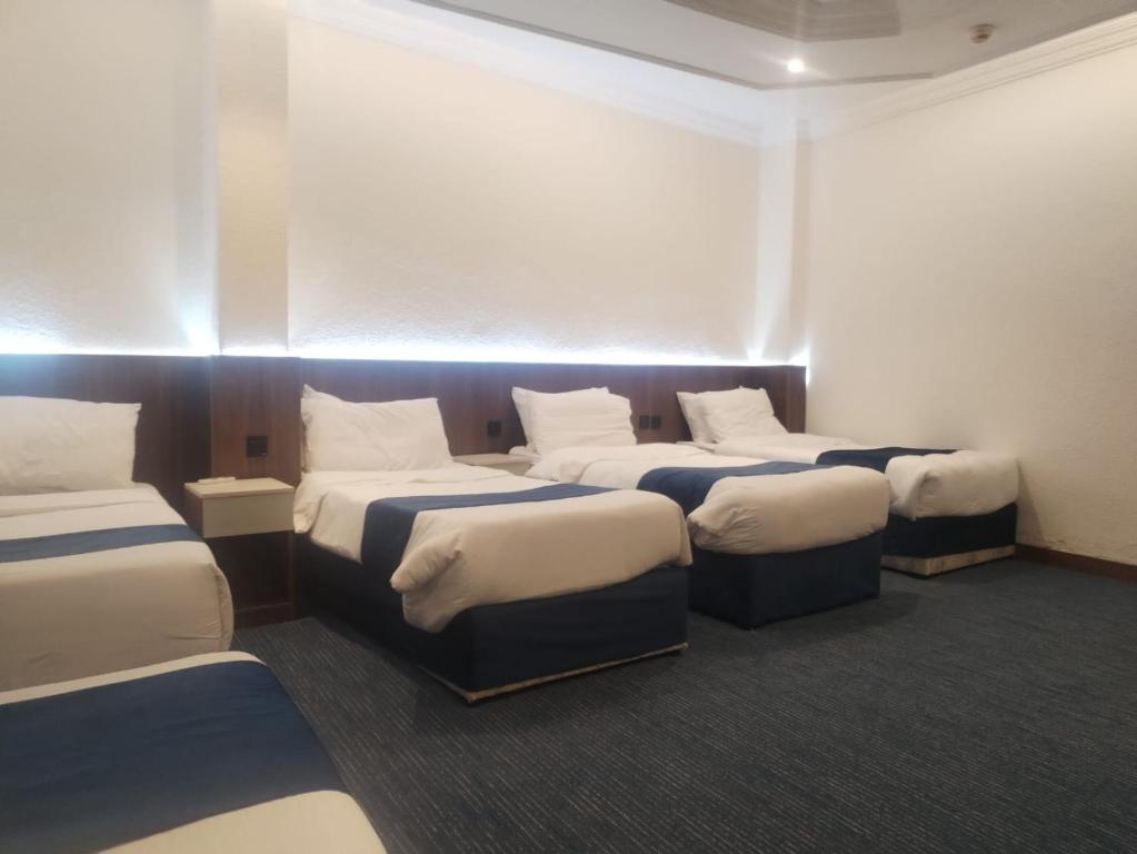 een kamer met vier bedden in een kamer bij Zwar Alharam Makkah Hotel in Mekka