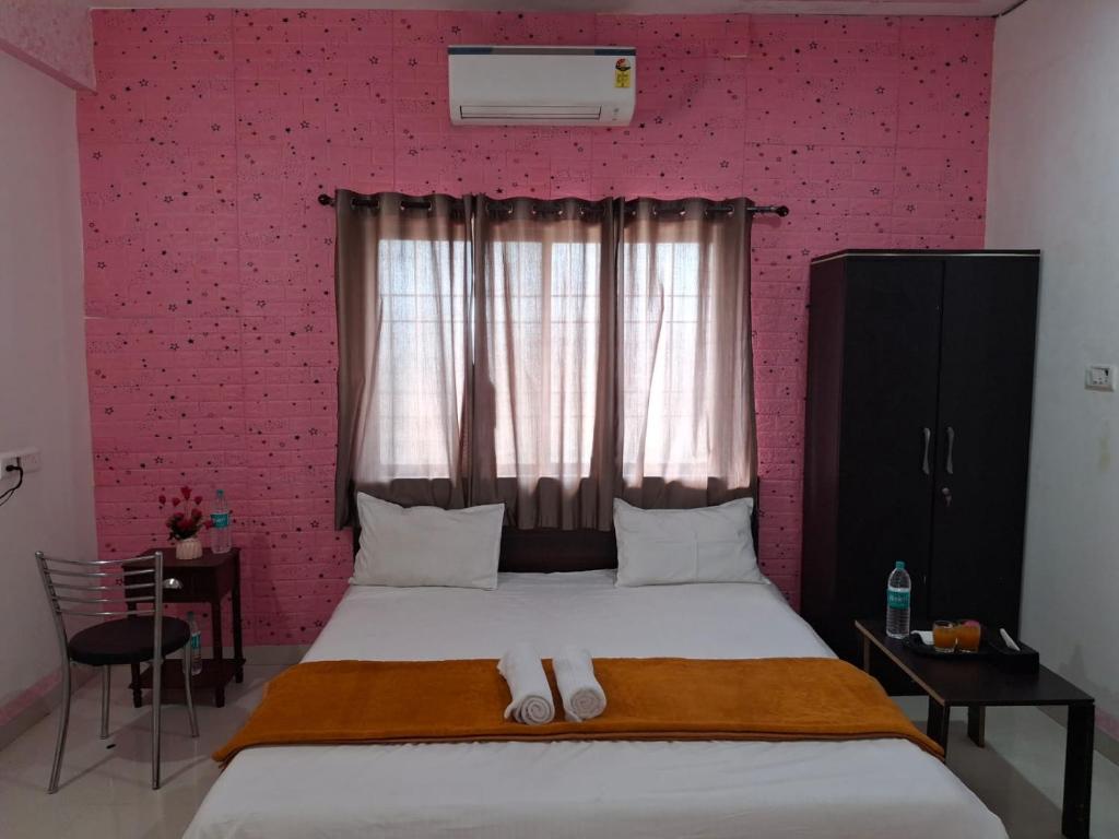 ein Schlafzimmer mit einem großen Bett mit einer rosa Wand in der Unterkunft Vrindavan Hotel and Restaurant in Malavli
